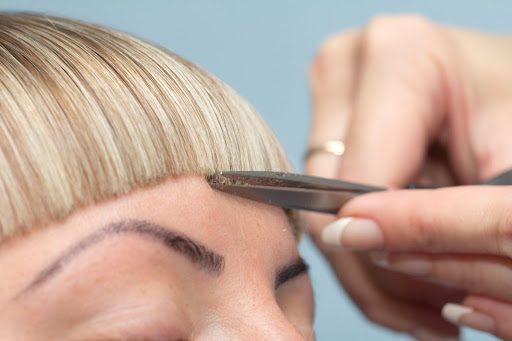 A close-up of a hairdresser trimming baby bangs.